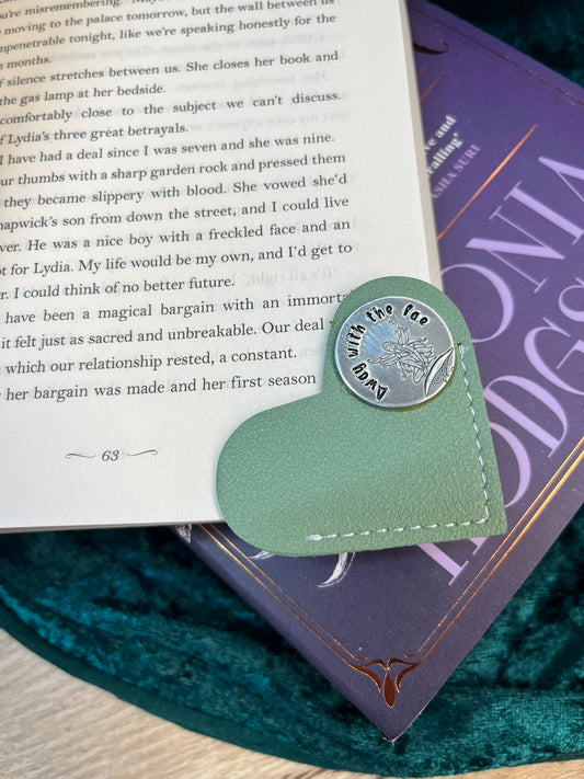 Heart-shaped leather bookmark with a metal charm on a book