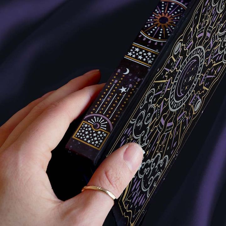 Detail of black journal with intricate gold and purple patterns, showing the spine.