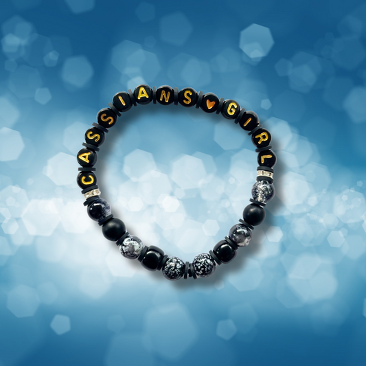 Black beaded bracelet with the words Cassians Girl, on a blue background.