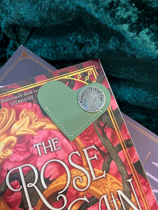 Green heart shaped bookmark with a metal disc engraved with a faery on a toadstool and words, Away with the fae.