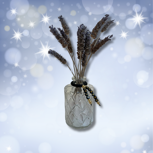 Glass vase with beads that say Book Dragon. Vase with lavender in it, shown on a light blue sparkly background.
