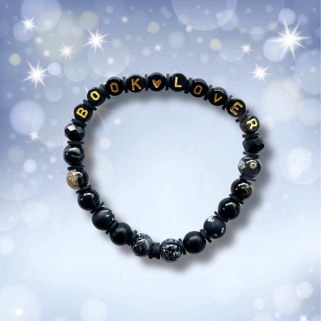 Black beaded bracelet with the words Book Lover, on a light blue background with stars.