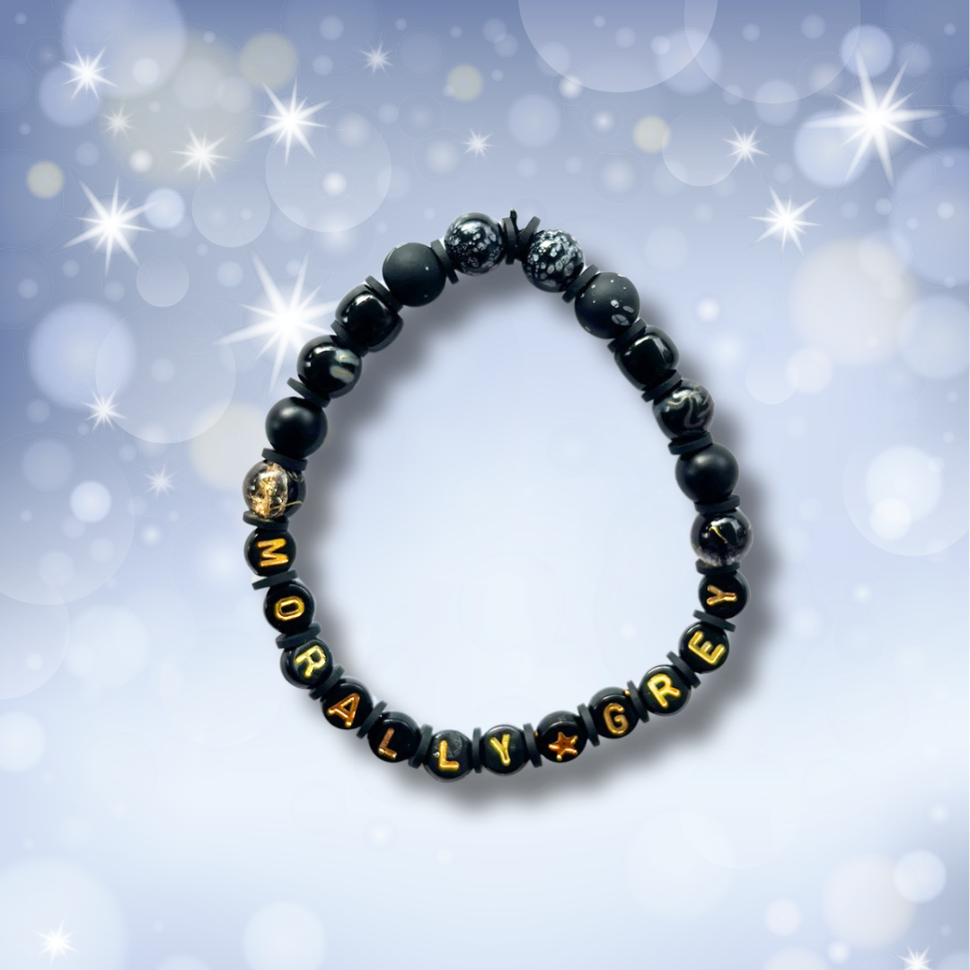 Black beaded bracelet with the words Morally Grey, on a light blue background with stars.