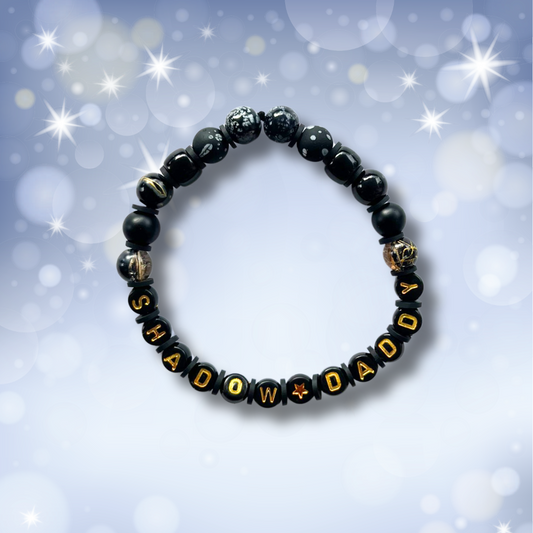 Black beaded bracelet with the words Shadow Daddy, on a light blue background with stars.