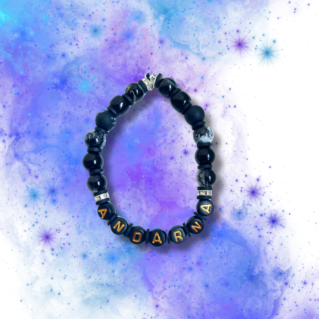 Black beaded bracelet with the word Andarna, on a purple and blue background.