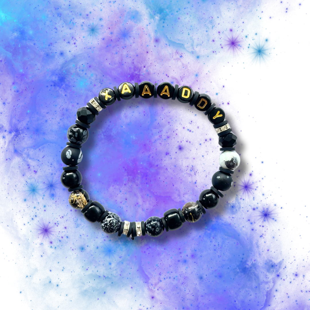 Black beaded bracelet with the word Xaaaddy, on a blue and purple background.