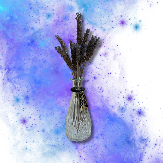Glass vase with beads that say Quest Squad. Vase with lavender in it, shown on a blue and purple background.