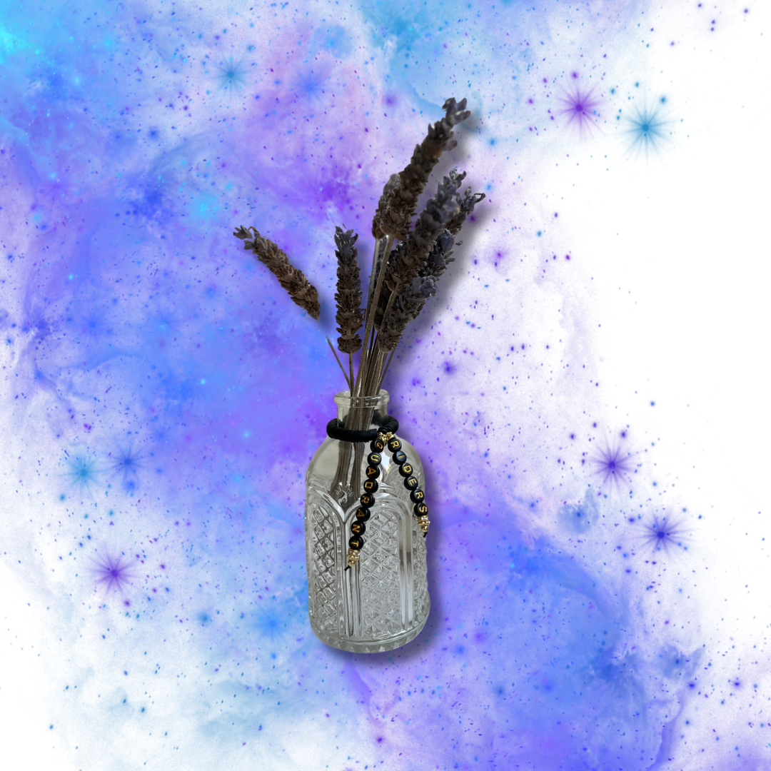 Glass vase with beads that say Riders Quadrant. Vase with lavender in it, shown on a blue and purple background.