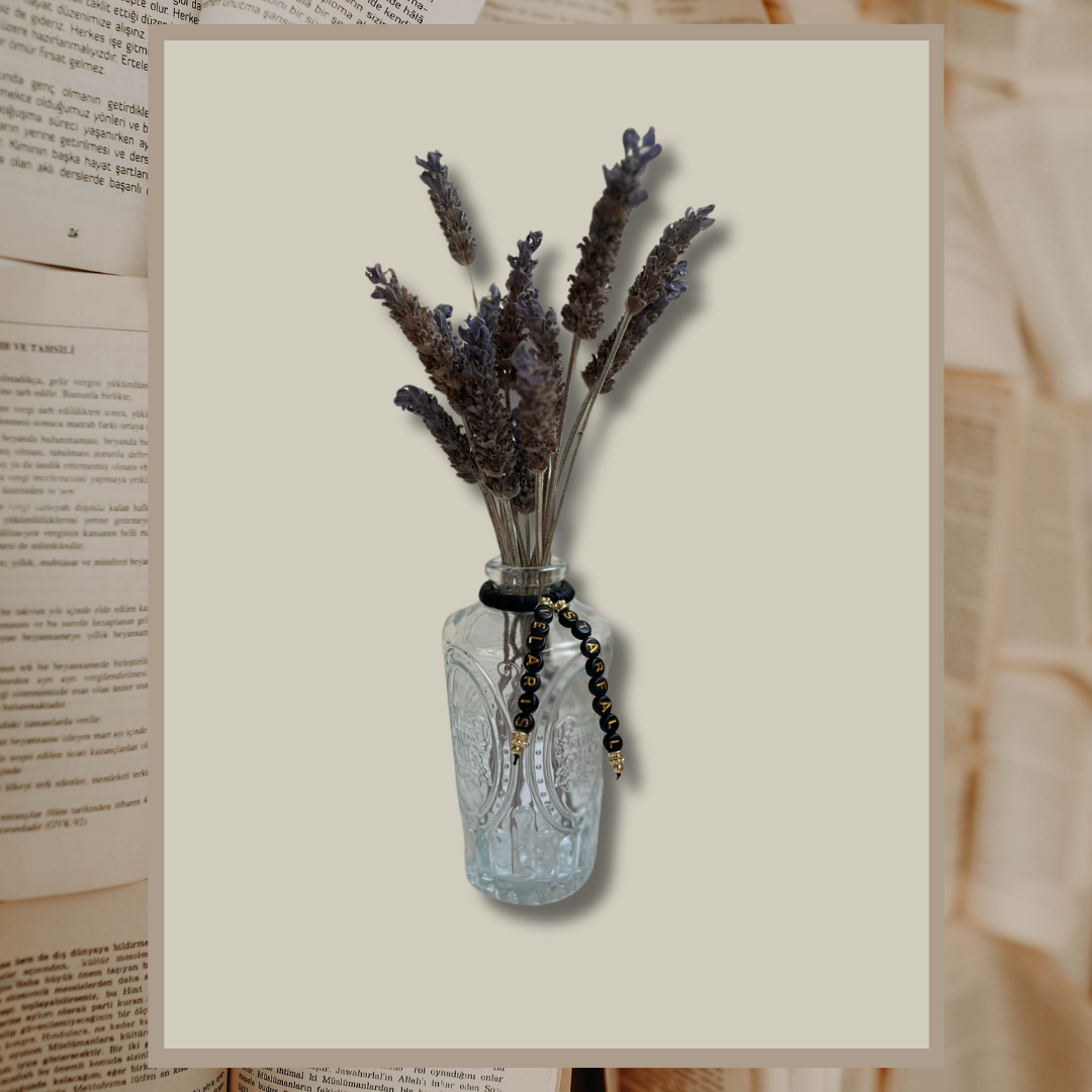 Glass vase with beads that say Starfall and Velaris. Vase with lavender in it, shown on an open books background.