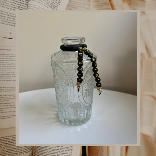 Glass vase with beads that say Starfall and Velaris. Shown on an open books background.