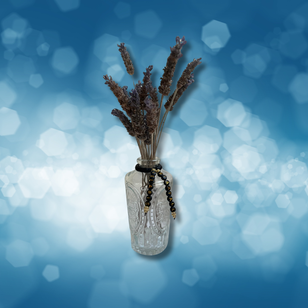 Glass vase with beads that say Starfall and Velaris. Vase with lavender in it, shown on a blue background.