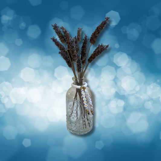 Glass vase with beads that say Tamlins Tears. Vase with lavender in it, shown on a blue background.