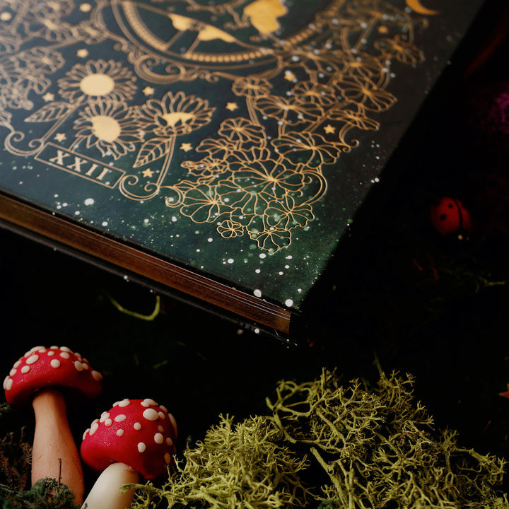 Dark green journal with intricate gold patterns, close up showing gold detailing and gold edges.